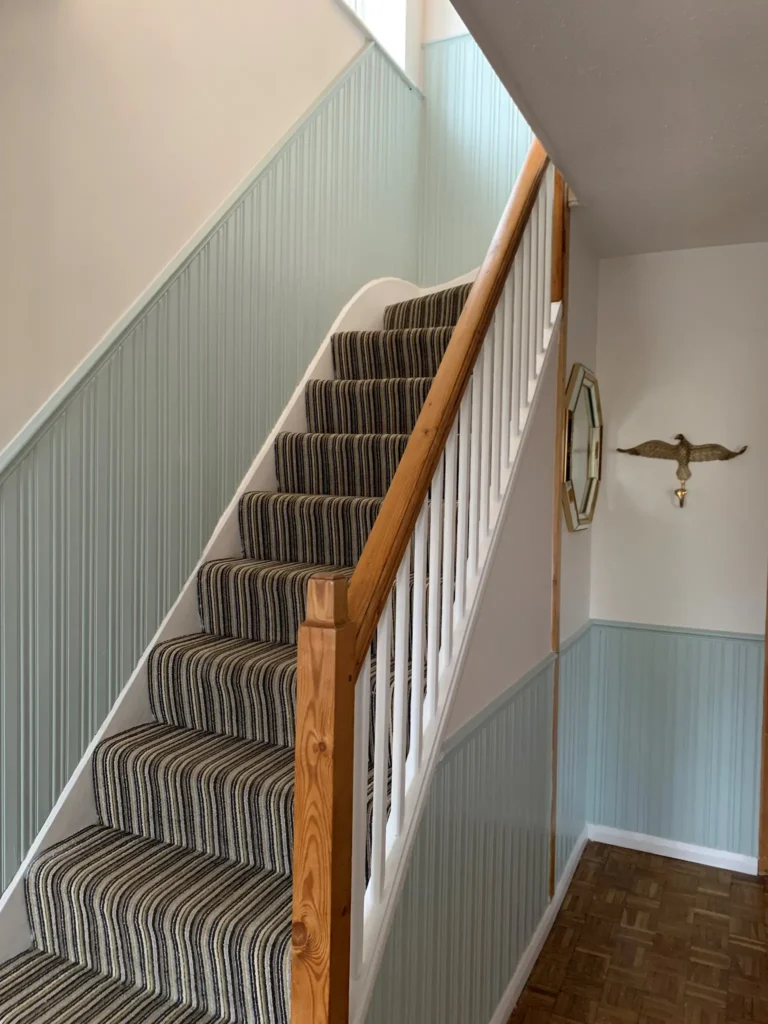 Finished hallway with painted panel work, stairs and finished handrail. Work completed by Haylock Enterprises.